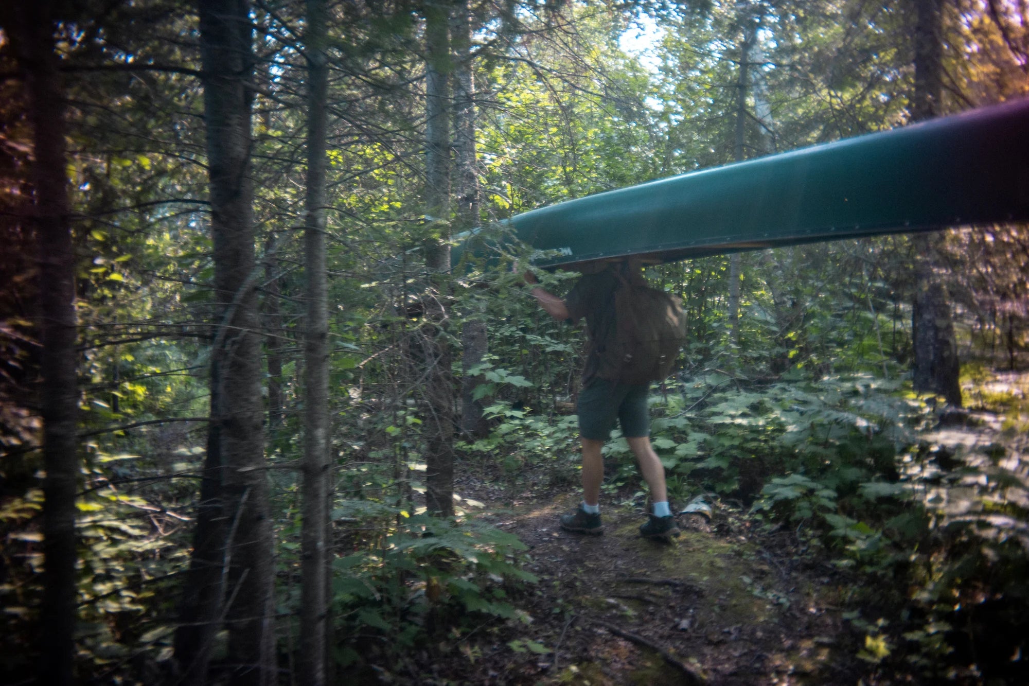 Vintage photo of a man portaging a canoe wearing a Duluth Pack Canoe Pack