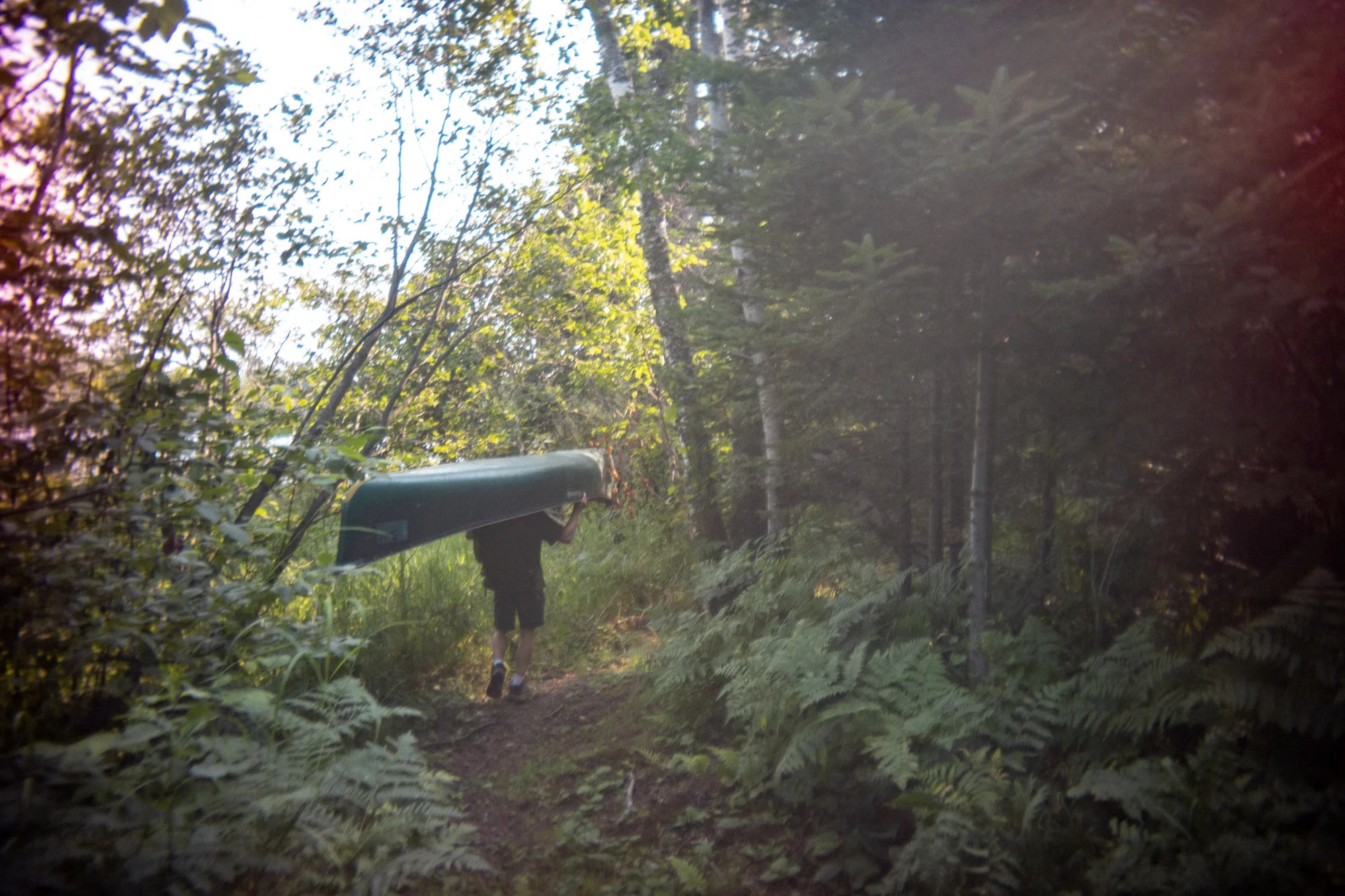 Vintage image of a man portaging a Duluth Pack Canoe Pack