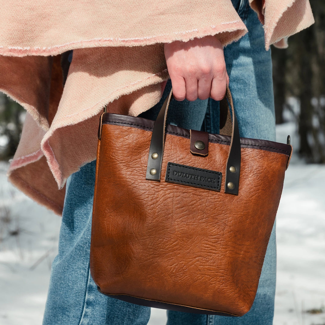 woman holding a duluth pack honeyberry tote wearing a shawl with a snowy background