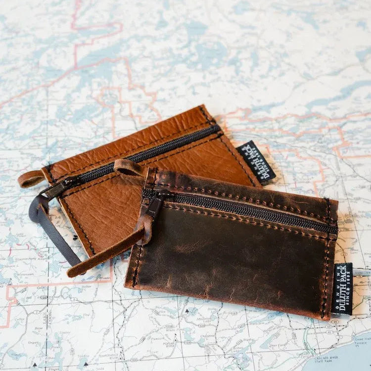Two Duluth Pack Bison Gear Stash leather wallets sitting on a topographical map 
